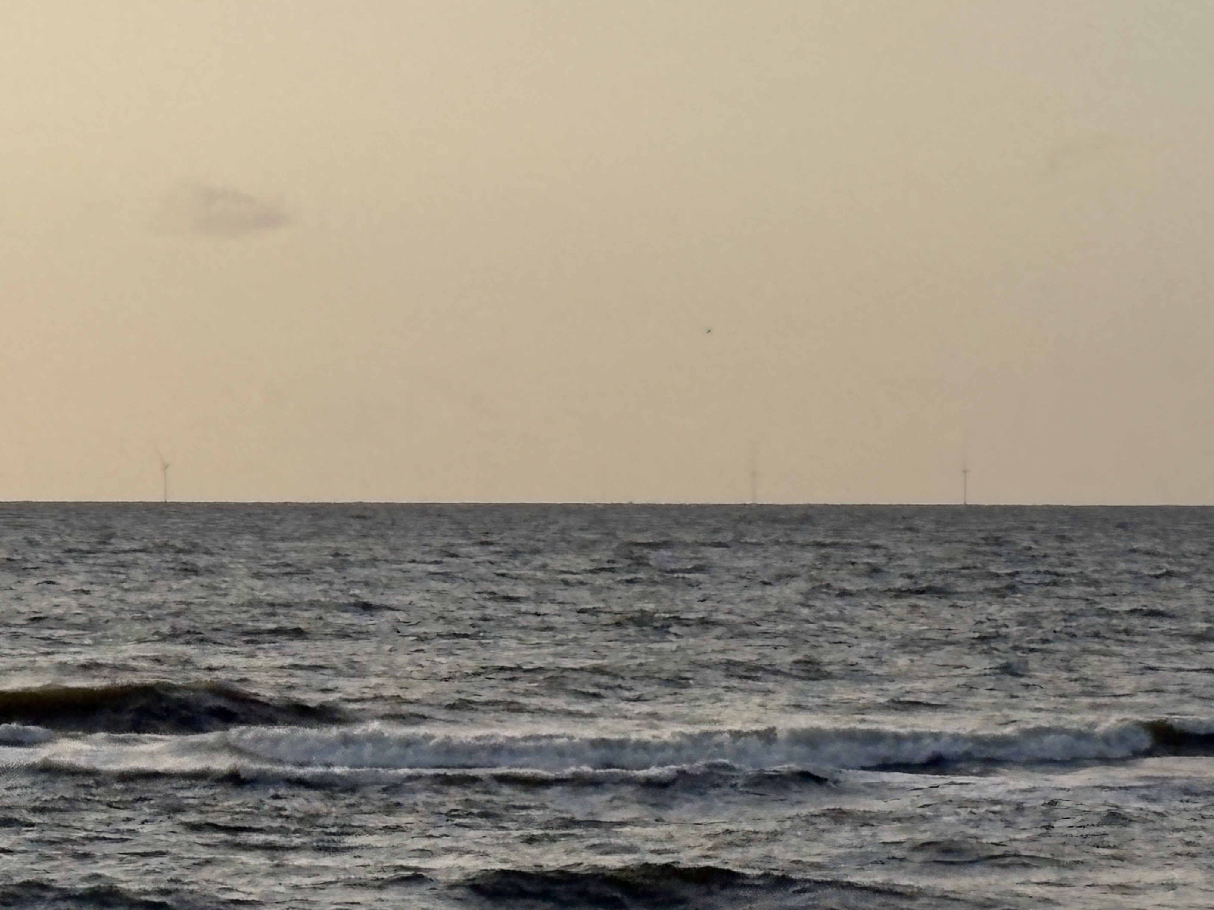 Turbiny wiatrowe farmy Baltic Power widziane z plaży w Lubiatowie